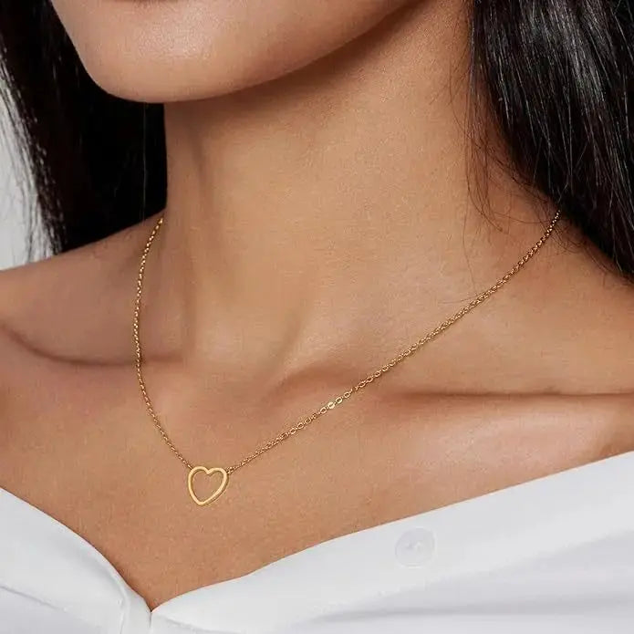Gold heart-shaped necklace on a person wearing a white top