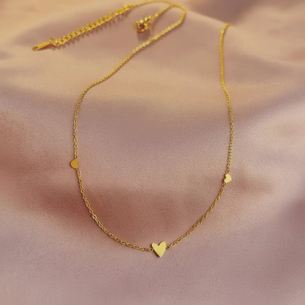 Gold necklace with a heart pendant on a soft pink background