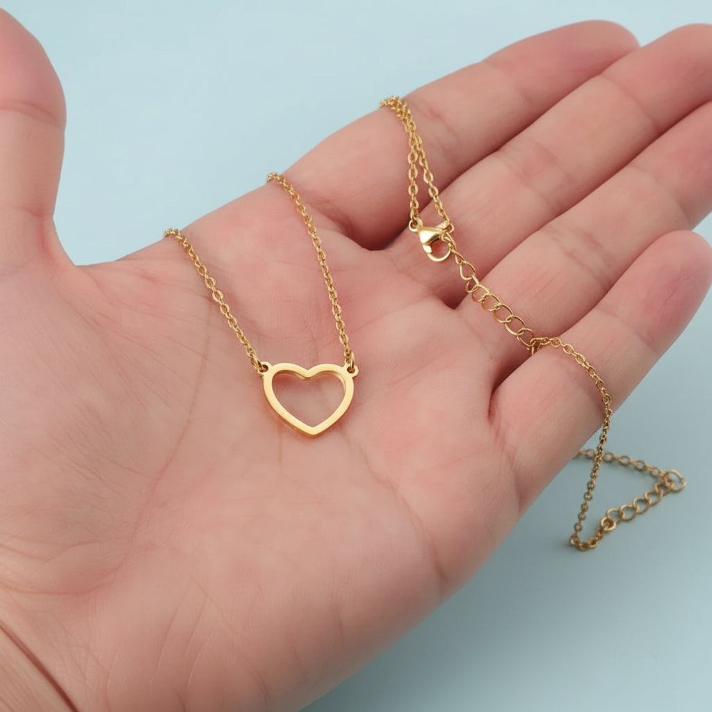 Gold heart-shaped necklace on a hand with a light blue background