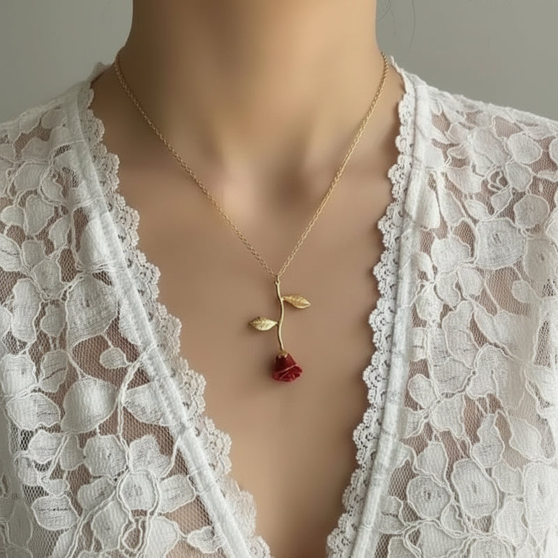 Gold necklace with a red rose pendant on a lace background