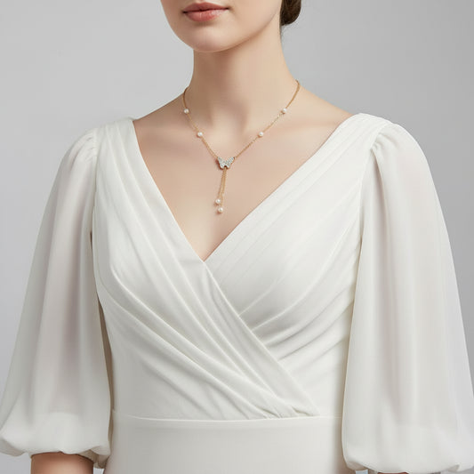 Gold necklace with a butterfly pendant and pearl accents on a mannequin.