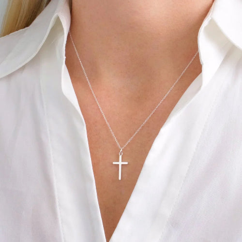 Silver cross necklace on a person wearing a white shirt