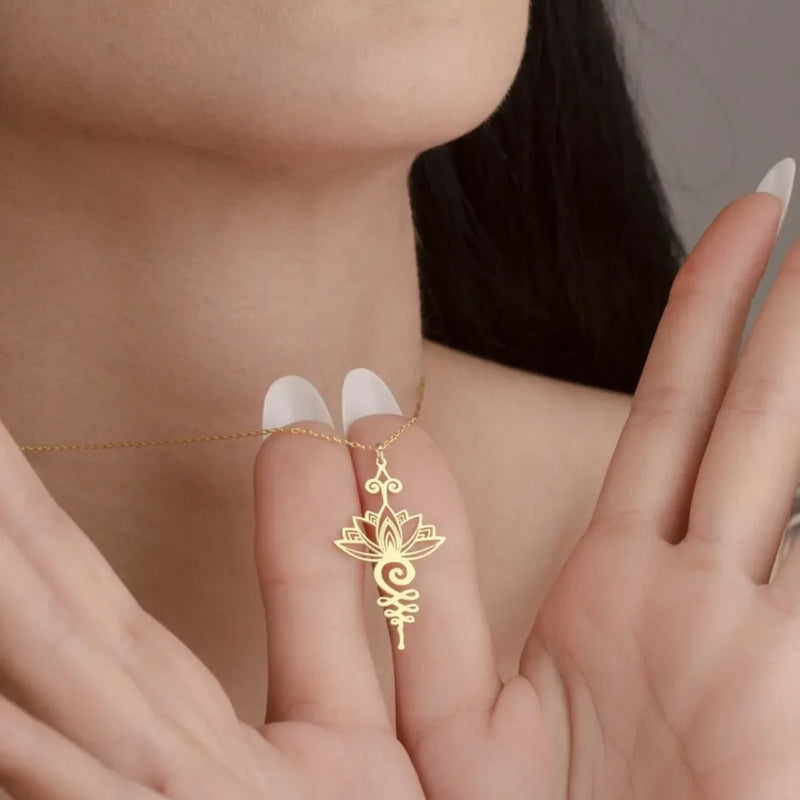 Gold necklace with a delicate pendant held by a person's hand